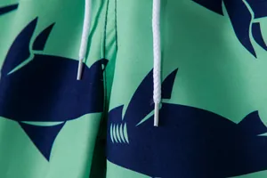 Macro detail of mint green swim trunks with navy blue shark print and drawstrings