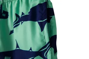 Detailed view of men's beach shorts featuring shark pattern print and pocket stitching