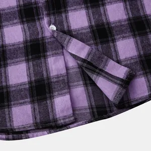 Close-up detail of purple and black plaid flannel shirt fabric with a white button.