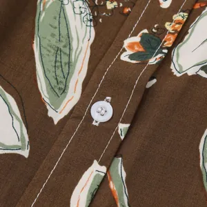 Gros plan d'une chemise de plage fleurie pour hommes avec bouton et coutures blancs.