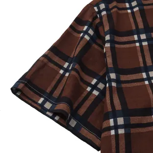 Detailed macro view of the sleeve and stitching on a brown plaid men's beach shirt.