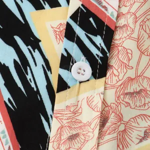 Macro view of vibrant floral print fabric and white button detail on a men's shirt