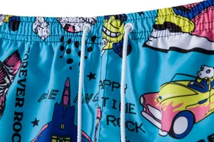 Close-up of men's blue beach shorts with colorful cartoon prints and elastic waist.