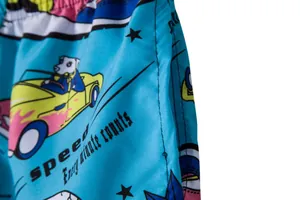 Detailed view of men's breathable blue beach shorts with cartoon car and dog prints