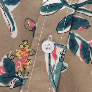 Gros plan sur le bouton et l'imprimé floral vibrant de cette chemise de plage pour hommes