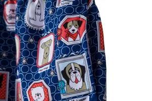 Close-up detail of men's beach shorts with colorful cartoon dog pattern on navy blue fabric.