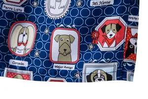 Close-up of blue men's beach shorts fabric featuring colorful cartoon dog print patterns.