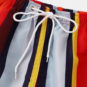 Close-up detail of vertical striped beach shorts featuring white drawstring and metal eyelets.
