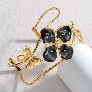 Detailansicht eines vergoldeten Armreifs aus Edelstahl mit schwarzer Emaille-Blume.