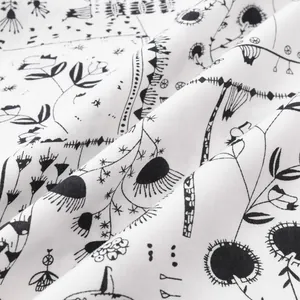 Macro view of soft white fabric featuring artistic black floral and botanical patterns