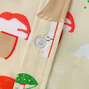 Close-up macro detail of men's casual shirt showing the button and mushroom print fabric