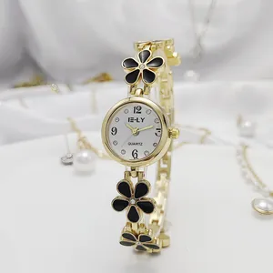 Close-up of gold-tone flower bracelet watch with black enamel petals and white dial