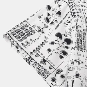 Close-up detail of short sleeve shirt with black abstract doodle print on white fabric.