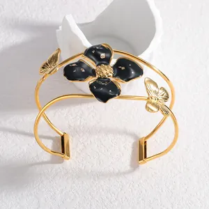 Eleganter offener Armreif aus goldfarbenem Edelstahl mit schwarzer Blume und Schmetterlingen