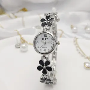 Close-up of elegant silver women's bracelet watch with black enamel floral design