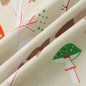 Detail of soft beige shirt fabric with colorful cartoon mushroom and tree patterns.