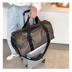 Grand sac de voyage de sport gris foncé professionnel placé sur une valise à roulettes argentée