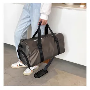 Personne portant un grand sac de sport gris foncé dans un cadre minimaliste