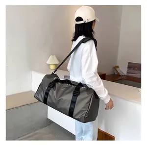 Sac de sport gris de grande capacité pour le voyage et le fitness, porté par une personne.