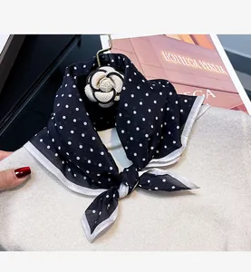 Detailed view of elegant black and white polka dot silk scarf on a white sweater
