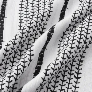 Détail rapproché des rayures verticales noires et motifs de feuilles sur tissu de chemise blanc.