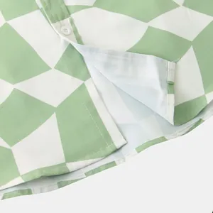 Close-up detail of mint green geometric pattern shirt with white button and hem stitching.