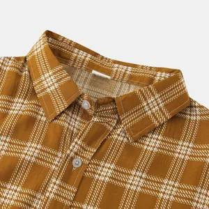 Close-up view of a brown and white plaid shirt collar with button-down fabric detail