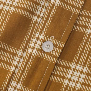 Macro view of men's brown plaid shirt fabric showing button and stitching details