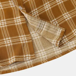 Detailed macro view of the brown plaid fabric texture and stitching on a men's short sleeve shirt