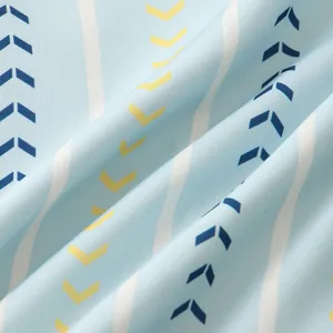 Close-up of light blue fabric with white wavy stripes and blue yellow arrow patterns.