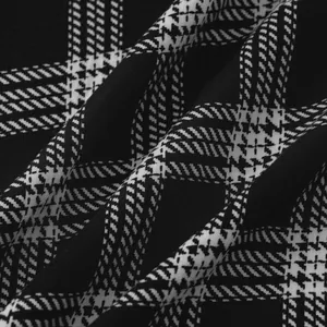 Close-up view of black and white plaid houndstooth fabric texture for men's slim fit shirt.