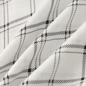 Macro detail of white fabric with black checkered pattern showing material texture