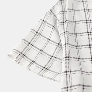 Close-up detail of a white men's short-sleeved shirt featuring a black windowpane check pattern