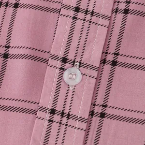Macro view of pink plaid shirt fabric texture detail with white button and stitching finish