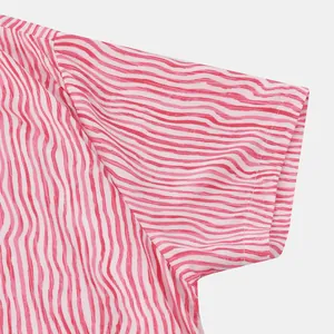 Gros plan montrant les coutures et le motif rayé rouge sur une chemise de plage pour hommes.