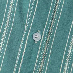 Macro detail of men's green striped shirt showing high-quality fabric and button.