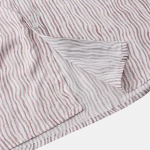 Détail en gros plan de l'ourlet d'une chemise homme à rayures marron et bouton blanc