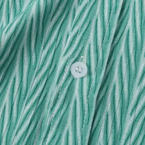 Gros plan sur le tissu à imprimé ondulé vert et le bouton d'une chemise de plage