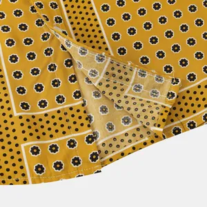 Macro view of men's yellow shirt featuring floral and polka dot patterns with fine stitching