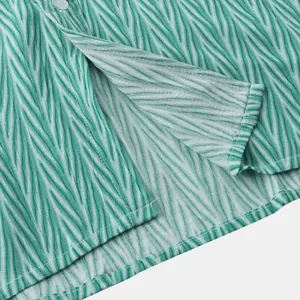 Gros plan sur les coutures de l'ourlet et le motif de vagues vertes d'une chemise pour homme