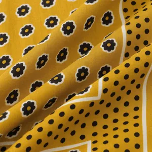 Macro view of mustard yellow shirt fabric with floral prints and polka dot details.