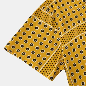 Close-up detail of yellow short-sleeve shirt with floral and polka dot stripe pattern