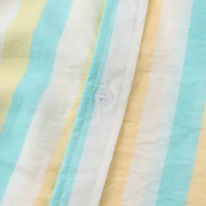 Détail macro de la texture du tissu et du bouton blanc sur une chemise de plage rayée pour homme.