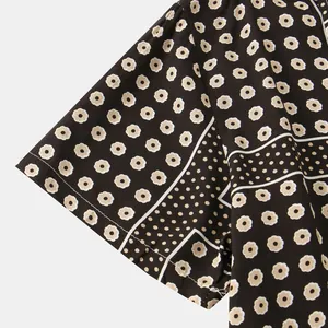 Close-up detail of men's short sleeve shirt showing black and beige vintage floral pattern