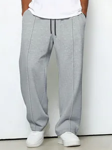 Detail of men's grey waffle knit trousers featuring a relaxed fit and drawstring waist.