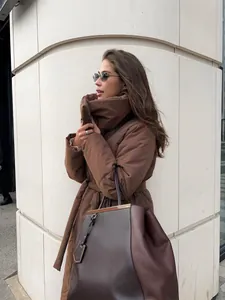 Side view of a woman wearing a long brown oversized puffer coat with a matching belt.