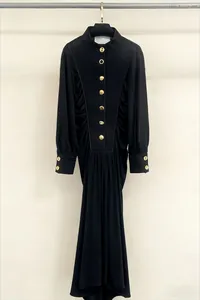 Elegant black maxi long-sleeve dress featuring vintage gold buttons and pleated waist detail.