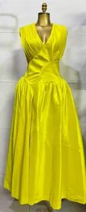 Gedetailleerd vooraanzicht van het geplooide lijfje en de taille van deze gele maxi-jurk.