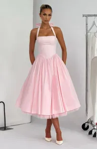 Elegant light pink halter midi dress featuring a bow neck and pleated voluminous skirt