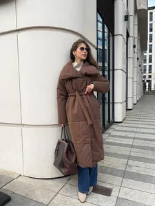 Street style view of a long brown puffer coat with tie-belt and quilted texture